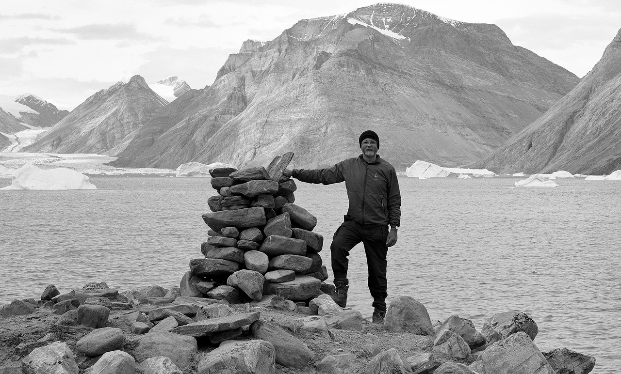 Iain Brownlie Roy standing by a stone cairn in a mountainous landscape